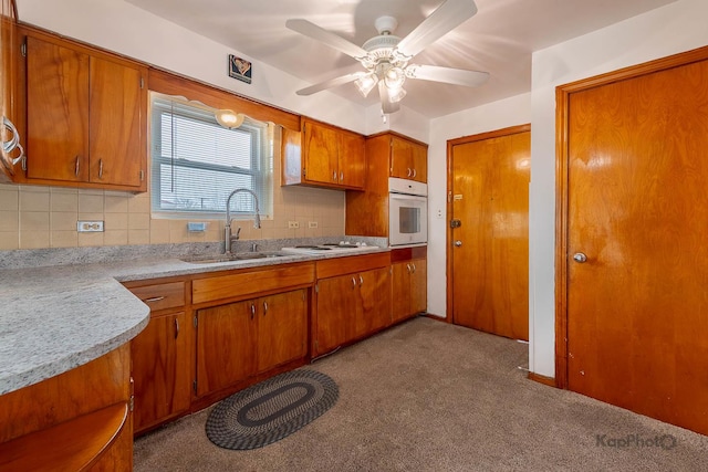 kitchen featuring a sink, white appliances, light countertops, brown cabinetry, and backsplash