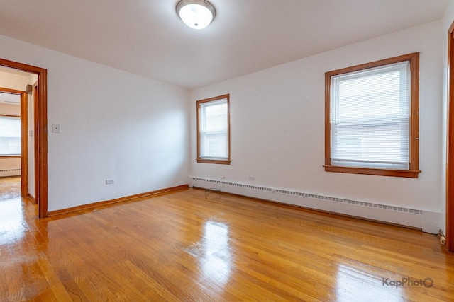 empty room featuring baseboards, a baseboard radiator, baseboard heating, and light wood-type flooring