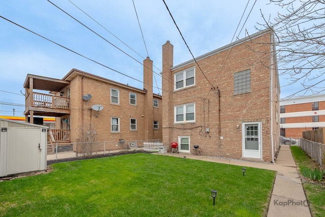 back of house with an outdoor structure, a fenced backyard, a shed, brick siding, and a lawn