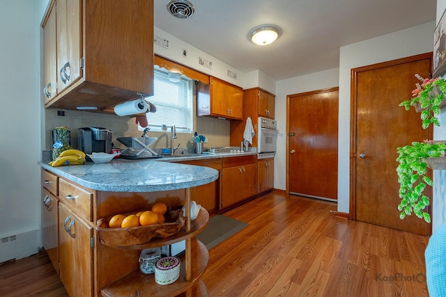 kitchen with open shelves, light wood-style floors, brown cabinetry, and white oven