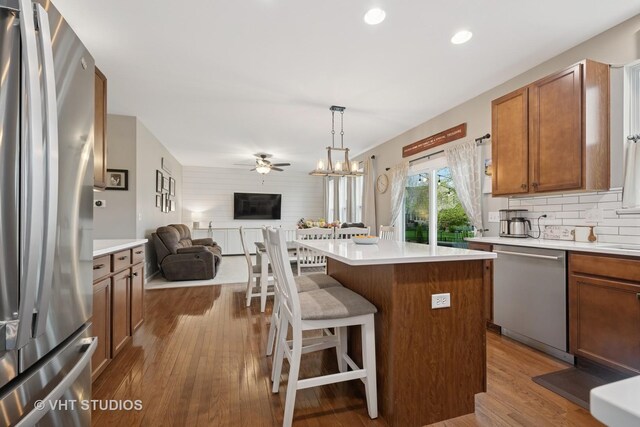 kitchen featuring appliances with stainless steel finishes, a ceiling fan, wood finished floors, and open floor plan