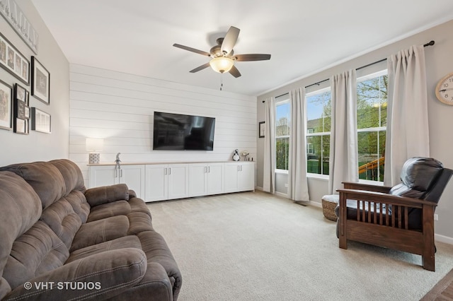 living room with ceiling fan, light carpet, and wood walls