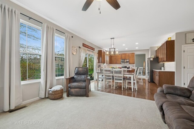 living area featuring visible vents, wood finished floors, baseboards, ceiling fan with notable chandelier, and recessed lighting