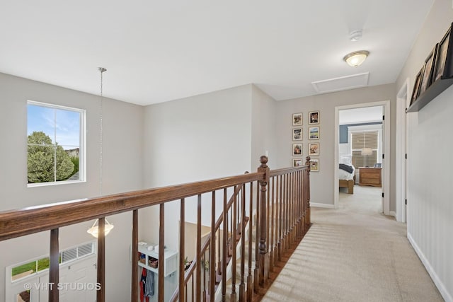 corridor with baseboards, attic access, light carpet, and an upstairs landing