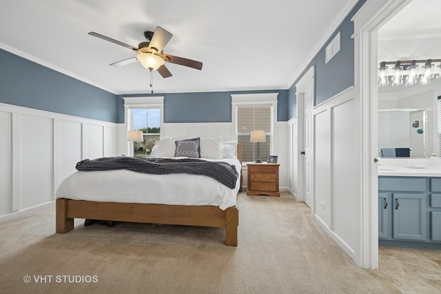 bedroom featuring light carpet, a wainscoted wall, and a decorative wall