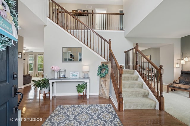 foyer featuring stairs, a high ceiling, baseboards, and wood finished floors