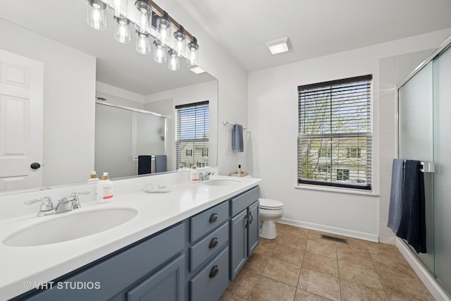 bathroom featuring double vanity, visible vents, a shower stall, and a sink