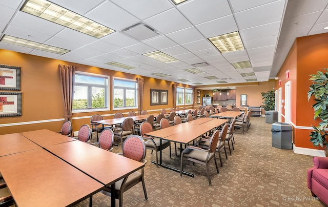 carpeted dining area featuring visible vents and a paneled ceiling