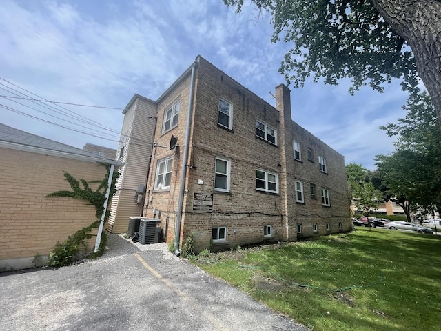 4819 Conrad St, Skokie, IL 60077 - view of side of property with a yard, brick siding, a chimney, and central AC unit