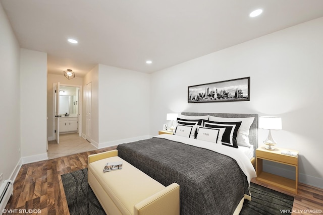 bedroom featuring baseboards, a baseboard radiator, ensuite bathroom, and wood finished floors