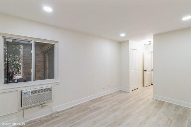 spare room featuring recessed lighting, baseboards, a wall mounted AC, and light wood-type flooring