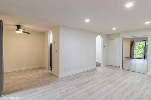 empty room with recessed lighting, arched walkways, ceiling fan, and light wood-type flooring