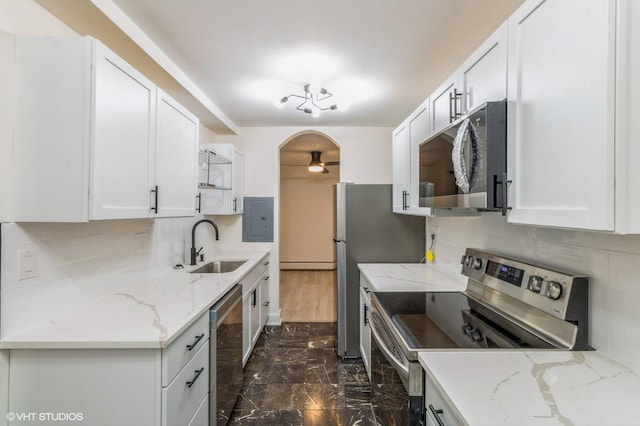 kitchen with a sink, appliances with stainless steel finishes, ceiling fan, and tasteful backsplash