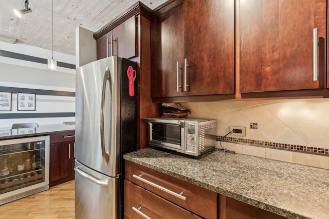 kitchen featuring decorative backsplash, light wood-type flooring, a toaster, freestanding refrigerator, and wine cooler