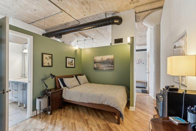 bedroom featuring visible vents, a high ceiling, baseboards, and wood finished floors