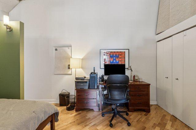 bedroom featuring a closet, baseboards, a towering ceiling, and wood finished floors