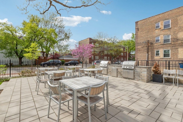 view of patio featuring grilling area, an outdoor kitchen, fence, and outdoor dining space