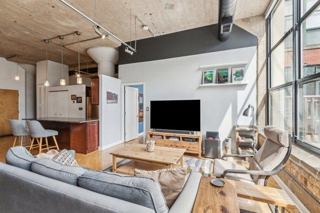 living area with track lighting, a towering ceiling, and wood finished floors