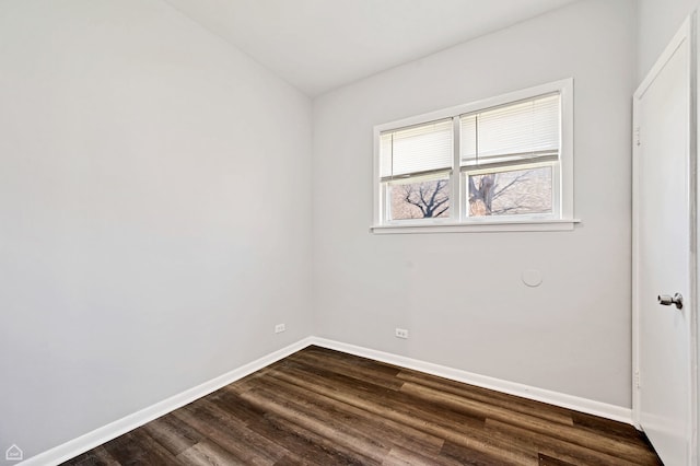 spare room featuring baseboards and dark wood-style floors
