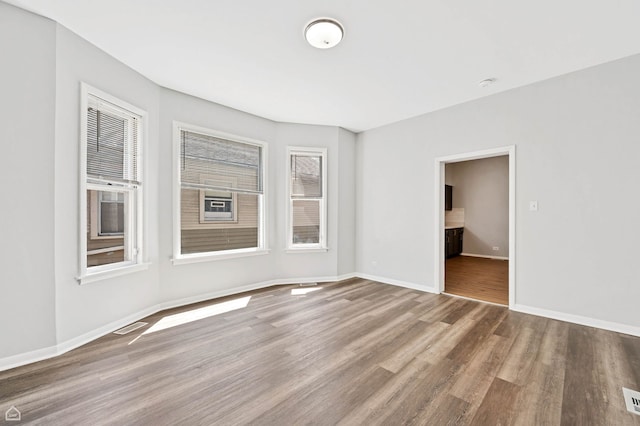 unfurnished room with visible vents, baseboards, wood finished floors, and a healthy amount of sunlight