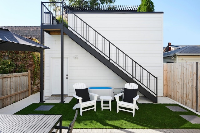 rear view of property with fence, a yard, stairs, and a balcony