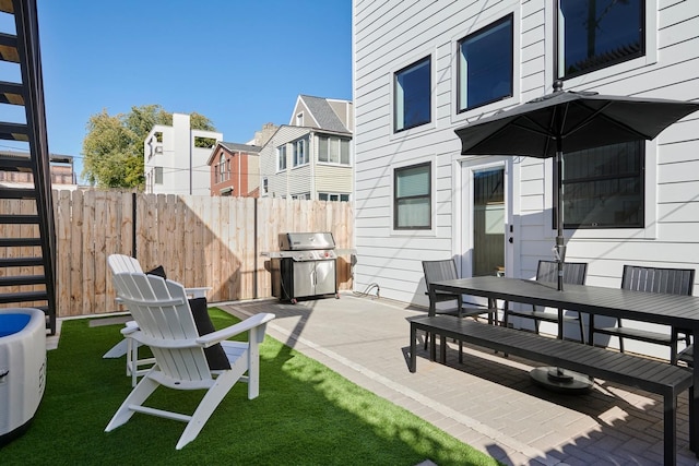 view of patio / terrace featuring a grill, fence, outdoor dining area, and a residential view