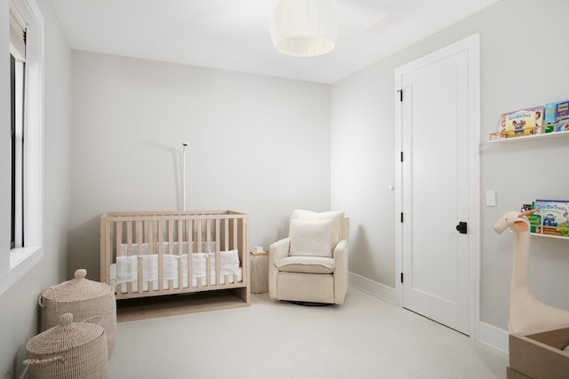 bedroom featuring carpet flooring, a nursery area, and baseboards