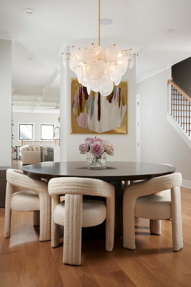 dining area with crown molding, stairs, a notable chandelier, and wood finished floors