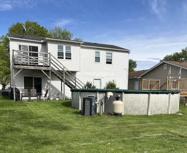 rear view of property with a lawn and a covered pool