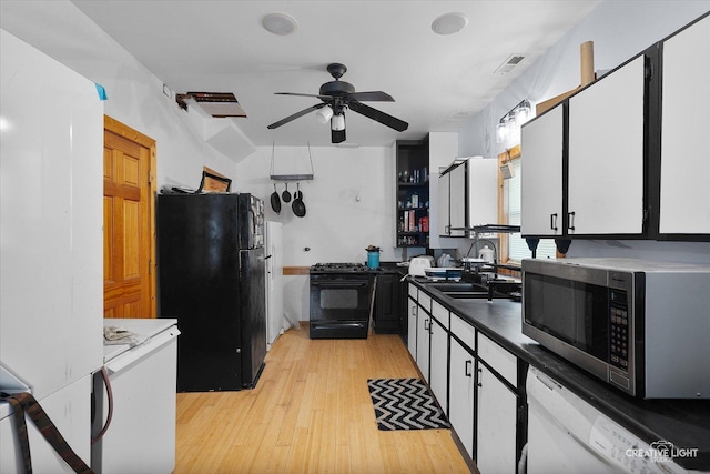 kitchen with black appliances, ceiling fan, light wood finished floors, a sink, and visible vents