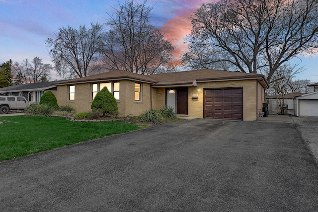 ranch-style home with driveway, a lawn, brick siding, and a garage
