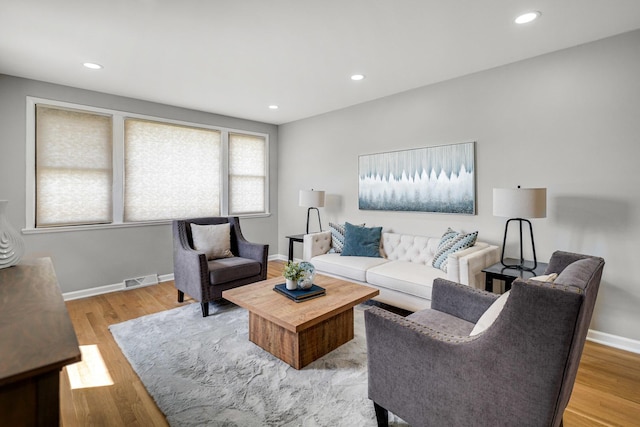 living area with light wood finished floors, recessed lighting, visible vents, and baseboards