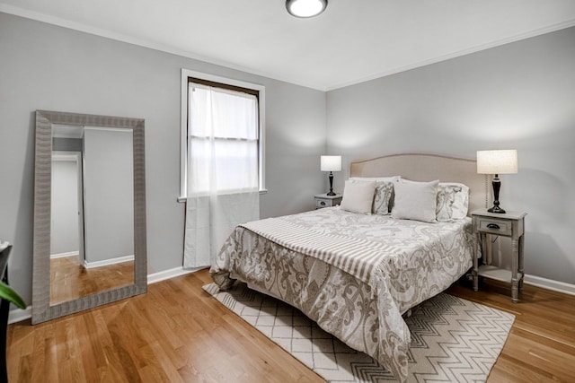 bedroom with wood finished floors, ornamental molding, and baseboards