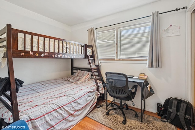 bedroom with crown molding and wood finished floors