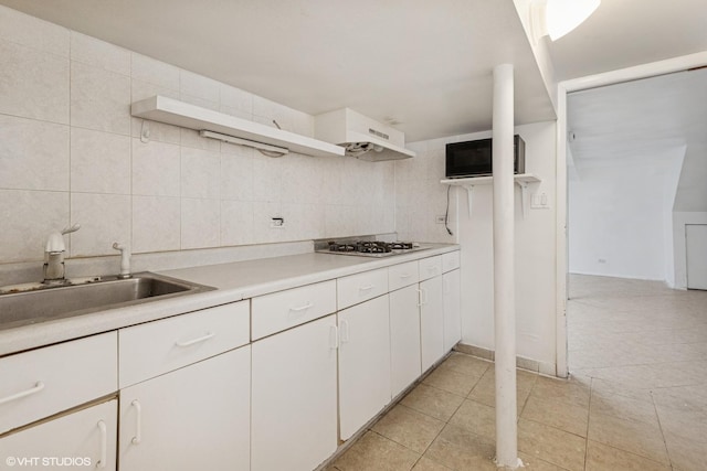 kitchen featuring decorative backsplash, open shelves, light countertops, white cabinets, and a sink
