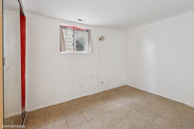 empty room featuring light tile patterned floors, visible vents, and baseboards