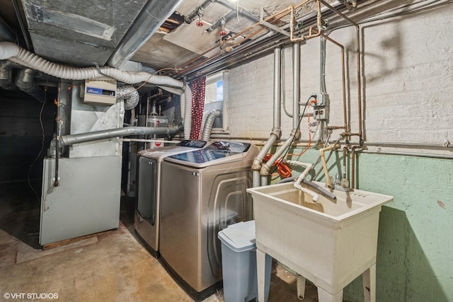 laundry area featuring heating unit, washer and clothes dryer, laundry area, and a sink