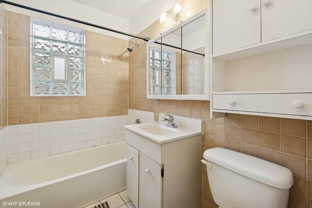 bathroom featuring a wealth of natural light, vanity, toilet, and tile walls