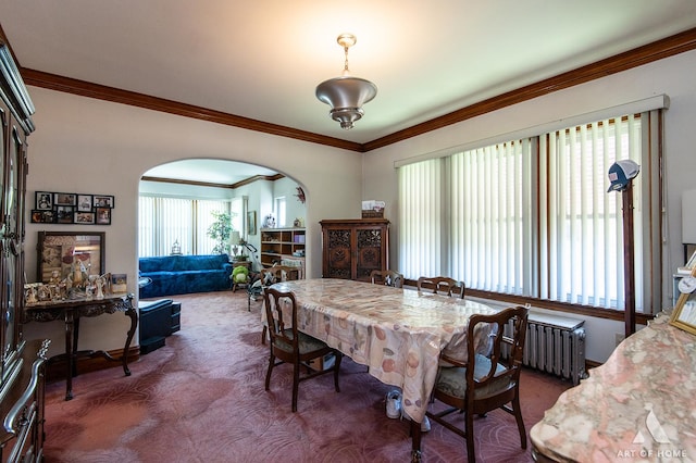 dining space with dark carpet, radiator heating unit, crown molding, and arched walkways