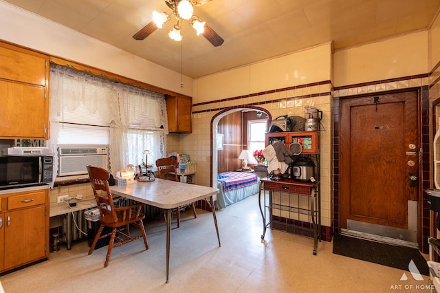 dining space featuring light floors, a ceiling fan, cooling unit, and arched walkways