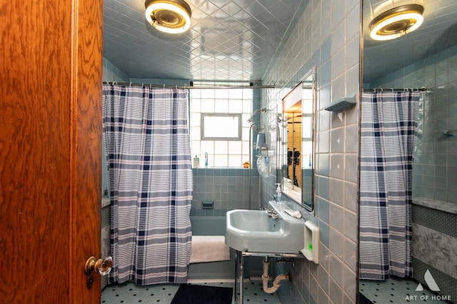 bathroom featuring tile walls, a sink, and tiled shower / bath