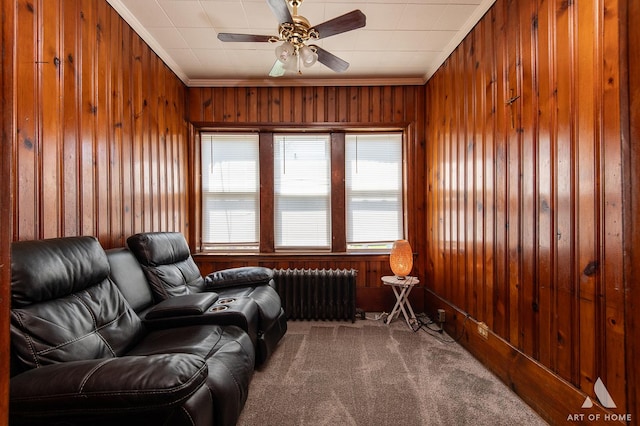 living area with radiator heating unit, ornamental molding, wooden walls, and carpet floors