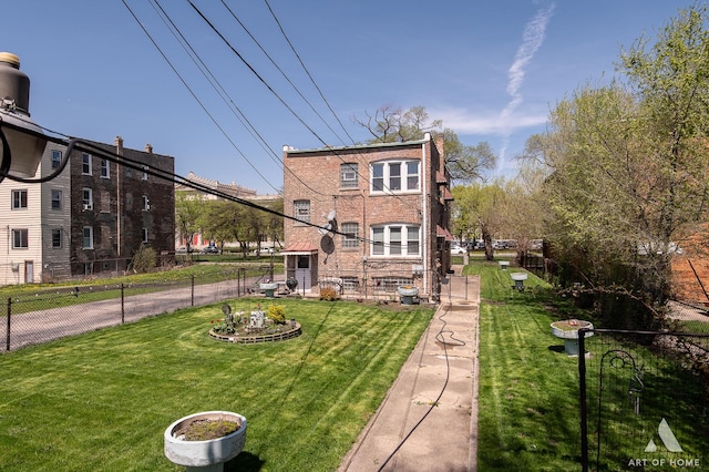 rear view of property featuring brick siding, fence, and a lawn