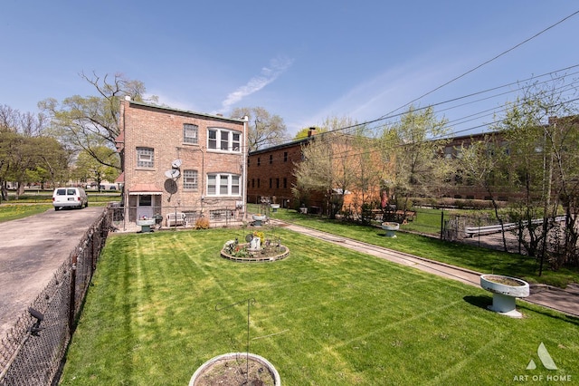 back of property with brick siding, a yard, and fence
