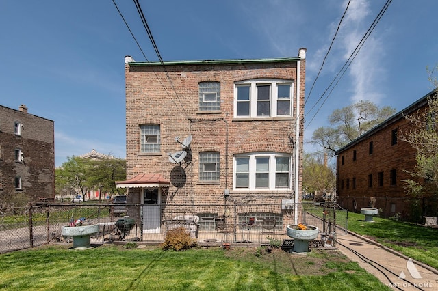 back of property with fence, a yard, and brick siding