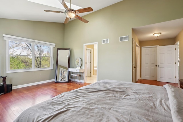 bedroom featuring high vaulted ceiling, wood finished floors, ensuite bathroom, baseboards, and ceiling fan