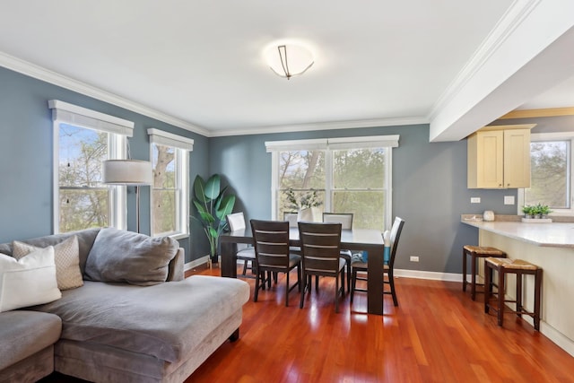dining space featuring ornamental molding, healthy amount of natural light, baseboards, and wood finished floors