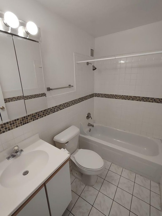 full bathroom featuring toilet, washtub / shower combination, tile patterned floors, tile walls, and vanity