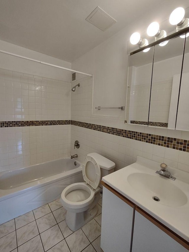 bathroom with toilet, bathtub / shower combination, vanity, tile patterned floors, and tile walls