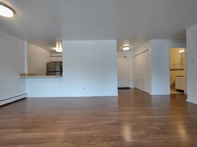 unfurnished living room with wood finished floors, baseboards, and baseboard heating